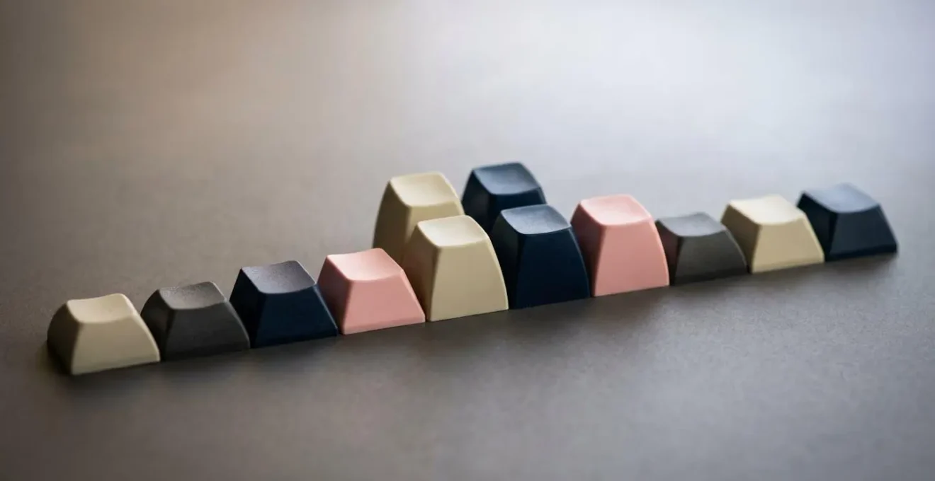 Arrangement artistique de touches de clavier colorées en PBT et ABS, montrant différents profils et textures