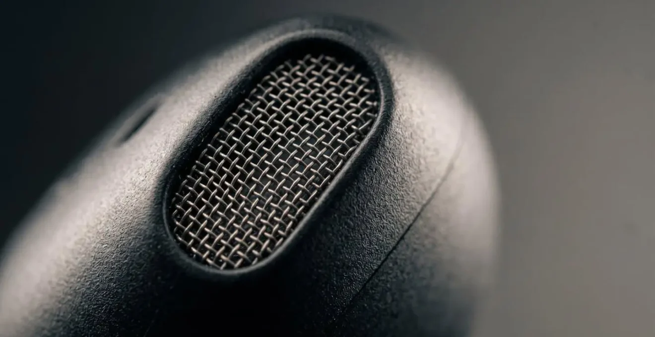 Gros plan sur des microphones intégrés dans des écouteurs sans fil captant l'environnement sonore