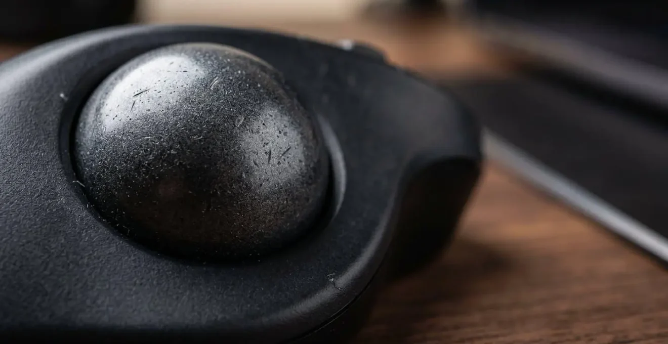 Gros plan sur un trackball ergonomique dans un espace de travail compact et organisé